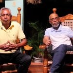 Conversatorio sobre la historia legal de Navarrete con dos participantes sentados en sillones de madera.
