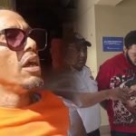 Hombre con gafas de sol junto a una imagen de un joven escoltado por agentes de seguridad en un pasillo.